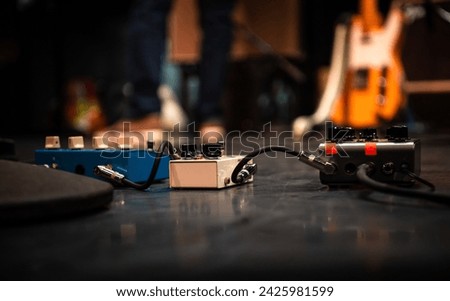 Close up of 3 connected guitar effects pedals on stage Royalty-Free Stock Photo #2425981599