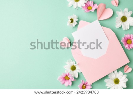 Spring awakening: a delicate array of petals and wishes. Top view of pink envelope with blank card, heart-shaped paper decorations, white and pink flowers on teal background with space for message Royalty-Free Stock Photo #2425984783