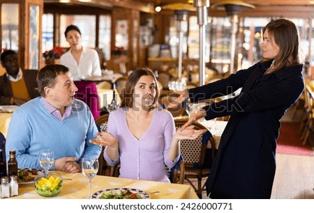 Woman quarreling with her husband who dating in restaurant with young mistress.