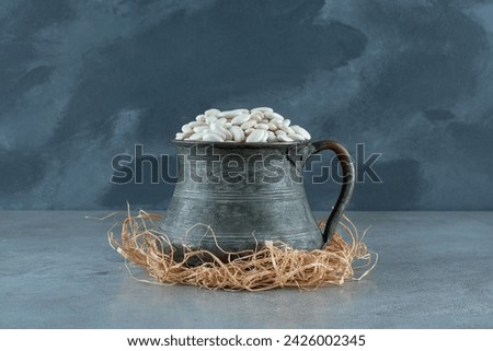 White beans in a metallic ethnic pot on dry grasses. High quality photo