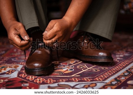 Close-up of 3-hole boots made of genuine leather worn indoors on the classic red carpet. Formal indoor concept photo with brown boots on Turkish red carpet