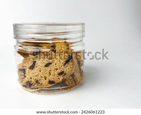 Almond cranberry Biscuits inside clear plastic container jar. Dry sweet and tasty bakery food. Object photography isolated on studio white background.