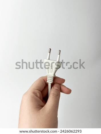 Hand holding white colored electronic object plug cable isolated photography on white studio background.