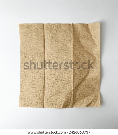 One single opened brown textured tissue paper with subtle flower design pattern. Object photography isolated on white plain studio background.