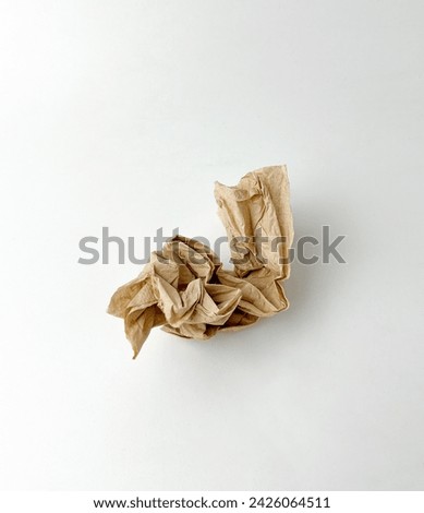 One crumpled brown textured tissue paper. Used bamboo tissue. Object photography isolated on white plain studio background.