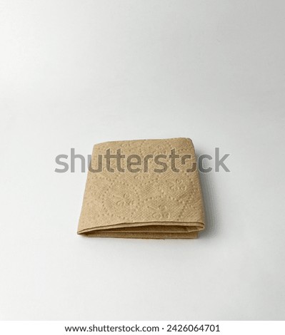 One square folded brown textured tissue paper. Object photography isolated on white plain studio background.