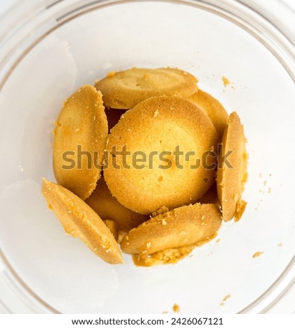 Close up round plain sweet bakery food biscuit treats inside clear plastic glass jar container. Object photography isolated on white studio background.