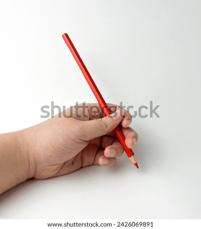 Human left hand holding red colored pencil with writing pose gesture. Photography isolated on white studio background.