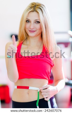 Young fitness woman with measure tape 