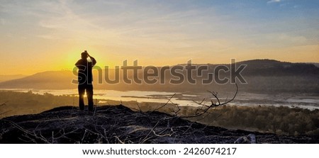 A man take a photo by mobile phone of sunrise with Knong river view the border of Thailand and Laos.