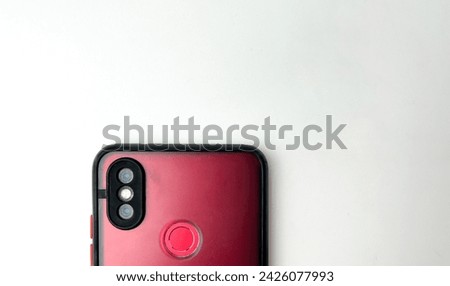 Red phone fingerprint area with old and aged phone case and two camera on the back of the mobile smart phone. Object photography isolated on horizontal copy spaced white background.