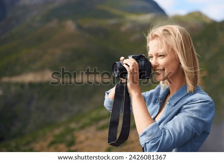 Happy woman, blonde and camera for outdoor photography, picture or sightseeing on mountain. Young female person or journalist with smile for photo, view or memory in natural environment in nature