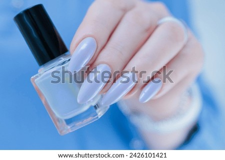 Woman's beautiful hand with long nails and light baby blue manicure
