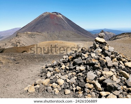 Tongariro Crossing with Mount Ngauruhoe in background. Cairn of stones and track summit.
