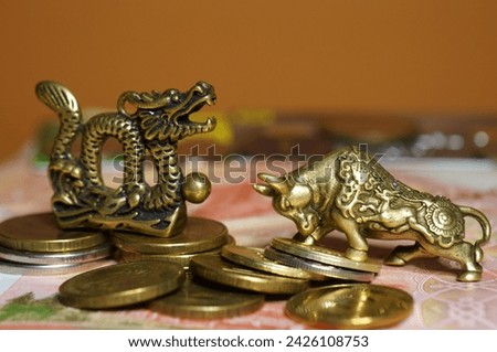 A statuette of a metal dragon and a bull with coins. Economics and finance.