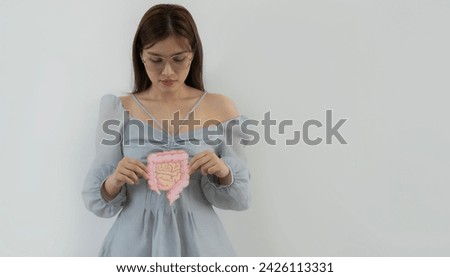 Portrait picture of young Asian woman holding intestine shape and looking happily over white wall background with copy space.
