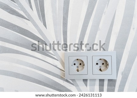 A closeup shot of two electrical outlets on a wall with a zebra print wallpaper, creating a striking pattern contrast in the house