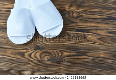 White slippers on wooden background. Top view with copy space.