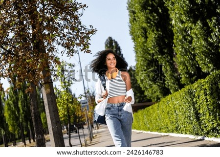 Photo of lovely cute girl with rucksack going on sidewalk enjoying walk in new city going downtown september weather outside
