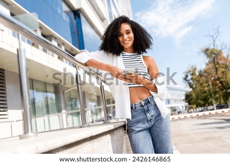 Photo of gorgeous adorable girl blogger in striped crop top writing post social media spending free time weekend sunny town outdoors