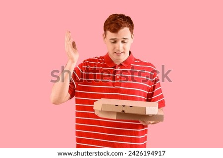 Thoughtful young redhead man with cardboard pizza boxes on pink background
