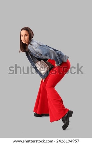 Stylish young woman in denim jacket on light background