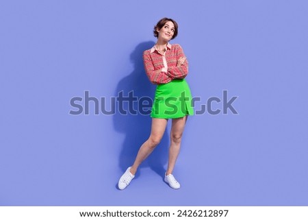 Full size photo of gorgeous positive woman dressed print shirt look at offer empty space arms folded isolated on blue color background