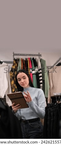 In clothing store. Female manager uses digital tablet to create stylish fashion collection. Small business owner concept