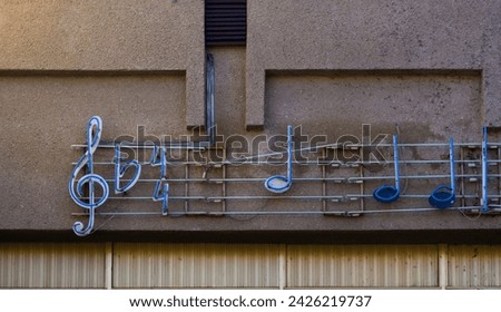 A bar of blue neon light music notation on the wall of the building.