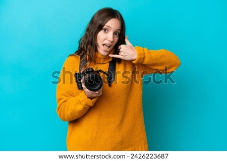 Young photographer woman isolated on blue background making phone gesture. Call me back sign