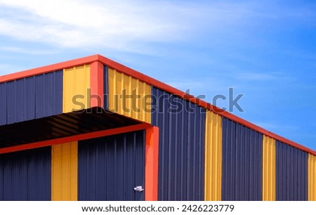 Yellow and black alternate colors pattern of aluminium industrial warehouse building against blue sky background, low angle and perspective side view