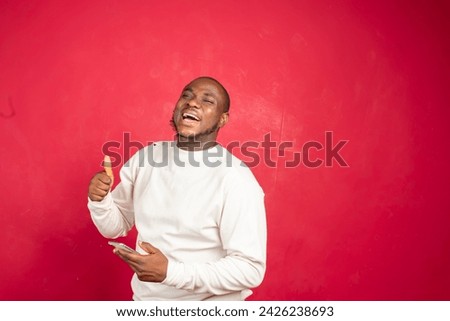 Overjoyed African man using smartphone sports betting, win money isolated on red background.