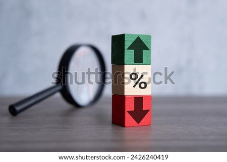 Magnifying glass and wooden blocks with percentage sign, up and down icon. Interest rate, stocks and currency exchange concept,