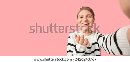 Happy young woman taking selfie on pink background with space for text