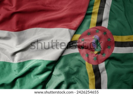 big waving national colorful flag of dominica and national flag of hungary . macro