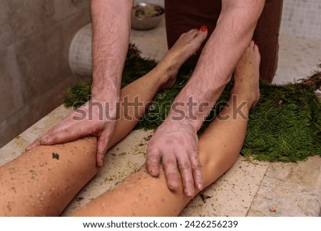 The man gently massages the womans thighs with his thumbs, starting at the knee and working his way up. She relaxes in the grass, feeling the soothing gesture on her bare legs Royalty-Free Stock Photo #2426256239