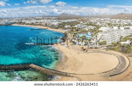 Playa de las Cucharas, Costa Teguise, Lanzarote: A perfect family beach with golden sand, turquoise waters, and a variety of water sports. Royalty-Free Stock Photo #2426263411