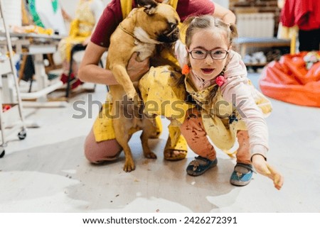 Cute little girl play with her dog. Child relaxing who have down syndrome in the art workshop. Creative activity for young children in school.