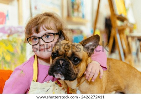Cute little girl with her dog. Child relaxing who have down syndrome in the art workshop. Creative activity for young children in school.