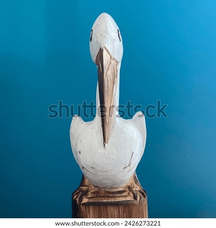 A pelican carving on a blue background.
