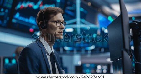 Professional Stock Exchange Trader Performing with Serious Focused Expression. Stockbroker Talking with Business Clients on a Call, Working on Computer, Speculating on Buying Shares for Day Trading Royalty-Free Stock Photo #2426274651