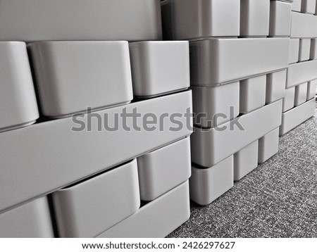 gray concrete flower pots, lined up in a warehouse in rows for sale. plastic white tubs of bricks stacked on top of each other. production of cheap design containers for plants, carpet