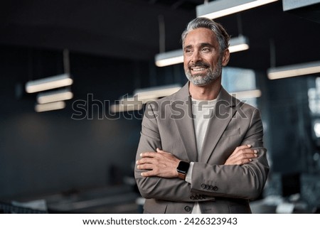 Happy confident mature 45 years old business man investor standing in office looking away. Middle aged rich business owner male ceo executive leader wearing suit at work thinking on future success. Royalty-Free Stock Photo #2426323943