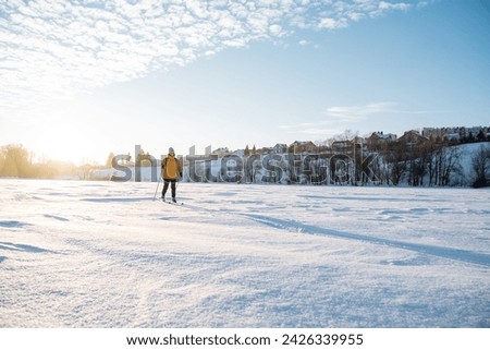 Man walking on snowy field in winter, setting sun, frozen lake, skiing training, silhouette of a man. High quality photo