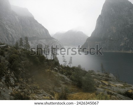 View of Hetch Hetchy water reservoir in a valley. Yosemite National Park. Beautiful foggy landscape photograph. 