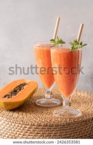 Two glasses of Papaya lassi, smoothie, juice on gray background. Freshness cold beverage of yogurt, water, spices, fruits and ice. Popular beverage in India and Sri lanka. Vertical format. Royalty-Free Stock Photo #2426353581