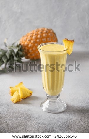Asian traditional Pineapple lassi on gray background. Freshness cold beverage made of yogurt, water, spices, fruits and ice. Popular beverage in India and Sri lanka. Vertical format. Royalty-Free Stock Photo #2426356345
