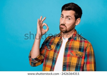 Photo of confident satisfied man with beard dressed checkered shirt showing okey recommend product isolated on blue color background