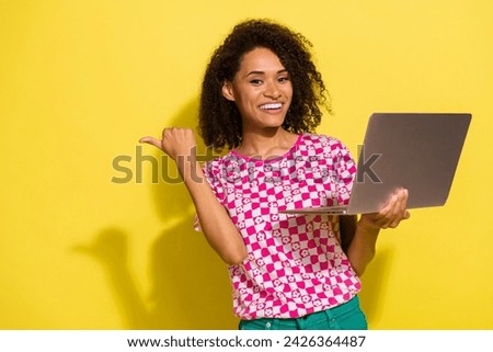 Photo of funny charming person toothy smile hold laptop indicate finger empty space isolated on yellow color background