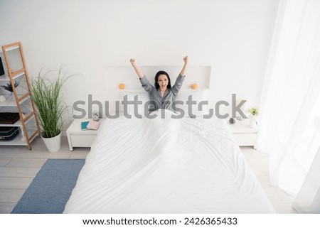 Photo portrait of lovely young lady lying bed raise fists celebrate wear trendy gray sleepwear isolated on white bedroom indoor interior